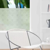 A graphic, linear representation of globes adorns privacy film for windows behind a contemporary chair.