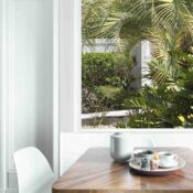 Dining table with fresh flowers and breakfast tray with coffee c