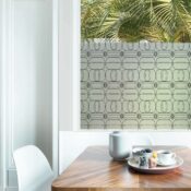 Delicate linear drawings of repetitive oversized jewels adorn a piece of privacy window film in in a family dining room.