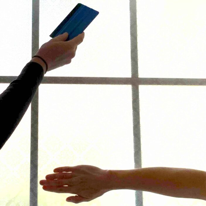 2 hands are pictured running across the surface of a window.