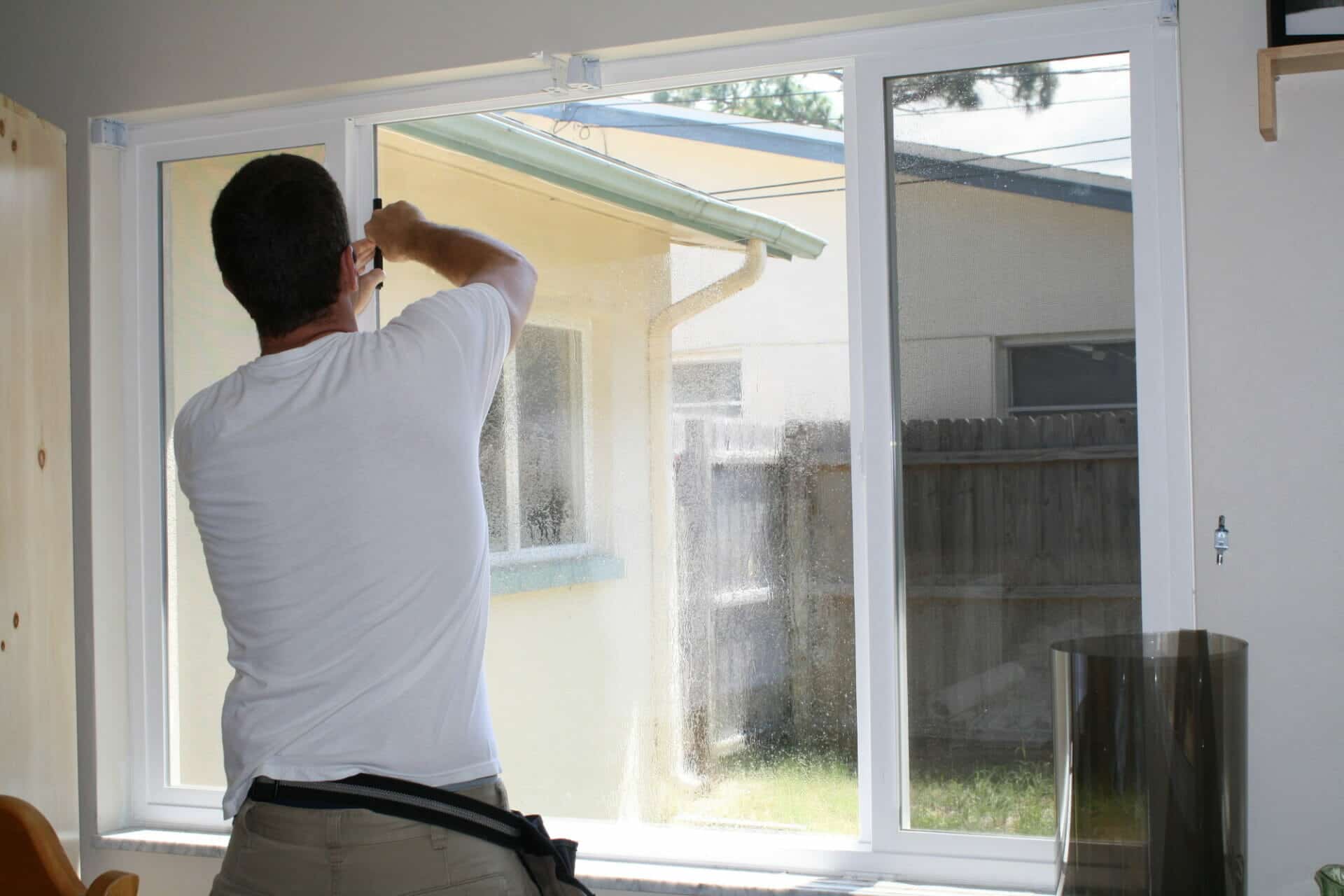 A man installs window privacy film on a curtainless window.